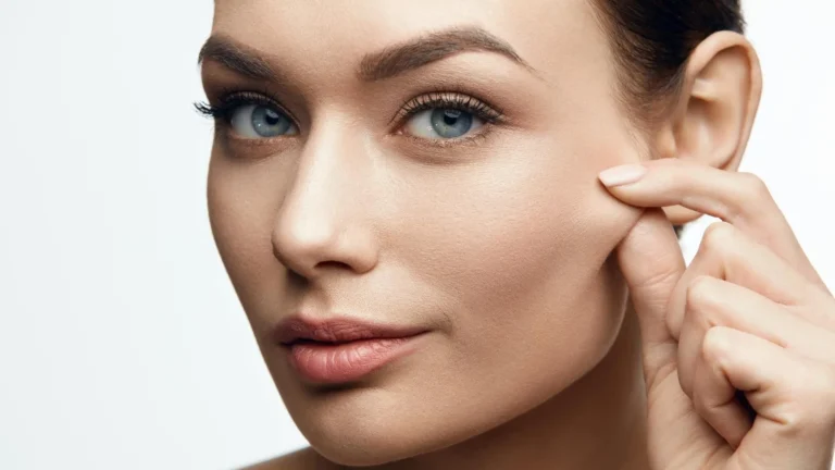 A woman gently pinches her cheek, highlighting smooth, flawless skin. Her expression is neutral, conveying a sense of calm and confidence.